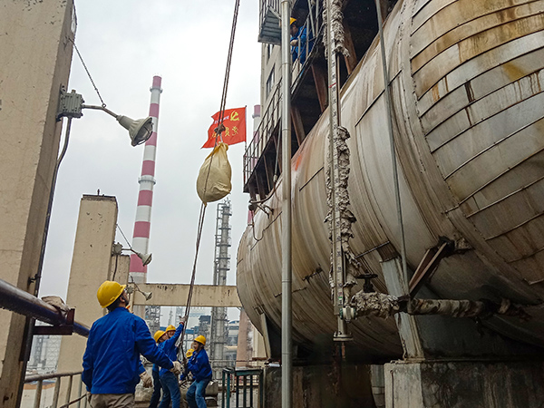 5月10日中午，在動力車間三期工藝除氧器地面，黨員突擊隊隊員用滑輪往工藝除氧器平臺運送鋼絲網(wǎng)，用以纏繞新填料.jpg
